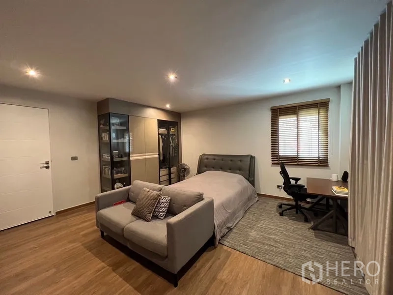 独立式住宅 出售在Chatuchak, Bangkok - 次卧配沙发休闲位、学习角与玻璃门衣柜，木地板。