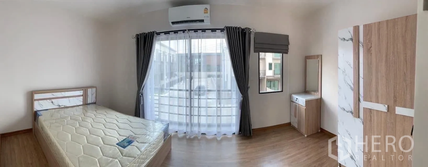 联排别墅 出租或出售在Prawet, Bangkok - 主卧带阳台，落地窗帘、衣柜与梳妆台。