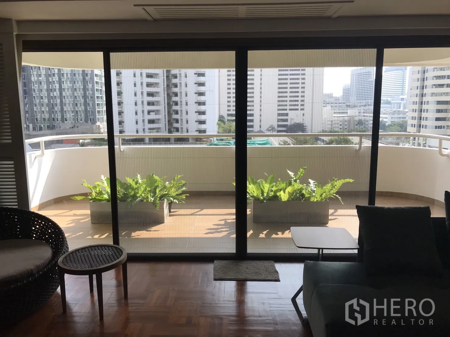 คอนโด ให้เช่าในBangkok - ระเบียงยาวปลูกต้นไม้ เห็นวิวสกายไลน์ผ่านประตูกระจกบานเลื่อน