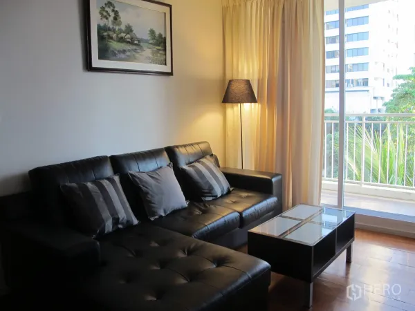 公寓 出租在Khlong Toei, Bangkok - 客厅配黑色皮沙发、落地灯，推拉门通向阳台。