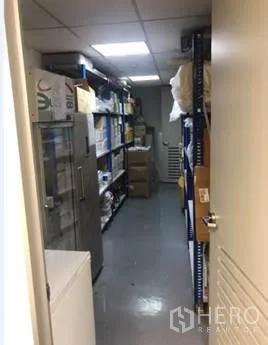 办公空间 出租在Khlong Toei, Bangkok - 狭长储藏室，金属层架与纸箱在明亮灯光下排列。