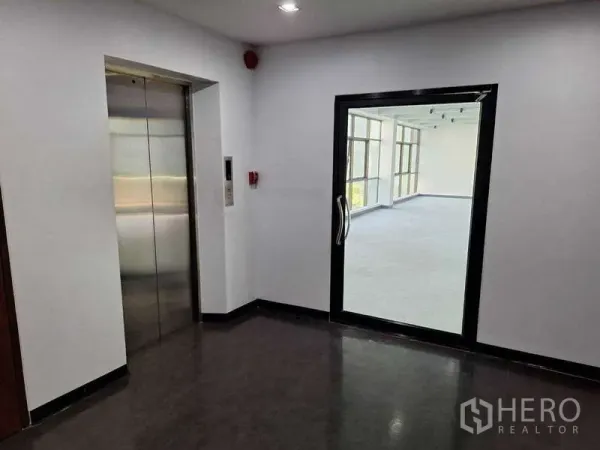 สำนักงาน ให้เช่า - โถงลิฟต์พร้อมลิฟต์สแตนเลส และประตูกระจกเข้าสู่พื้นที่ออฟฟิศที่สว่าง