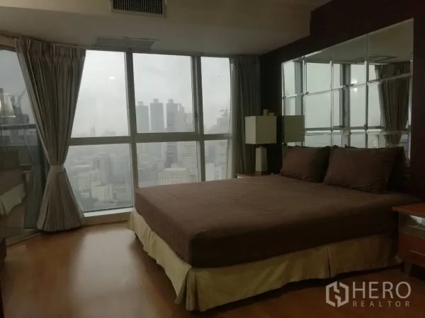 公寓 出租在Khlong Toei, Bangkok - 主卧角落落地窗，俯瞰城市天际线。