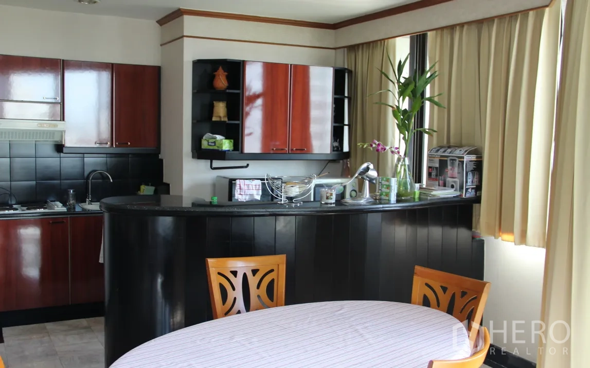 คอนโด ให้เช่าในKhlong Toei, Bangkok - ครัวเปิดตู้สีเข้ม ผนังกระเบื้องสีดำ เคาน์เตอร์บาร์โค้ง และมุมทานอาหารติดหน้าต่าง