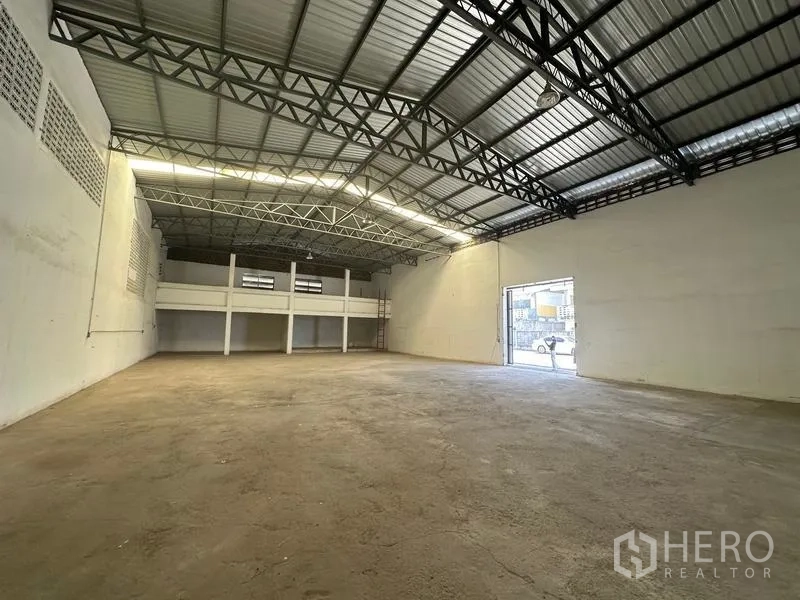 货栈 出租在Mueang Pathum Thani, Pathum Thani - 仓库内部通透无柱，高钢桁架屋顶、光滑混凝土地面，后方设有夹层可作办公或储物。