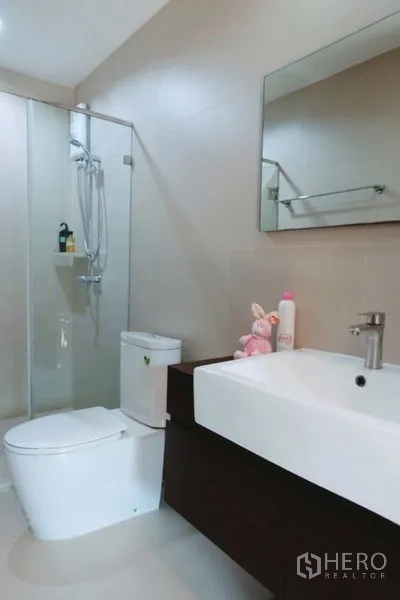 Townhouse for rent in Khlong Toei, Bangkok - Modern bathroom with glass shower enclosure, toilet and wide vanity with rectangular basin.