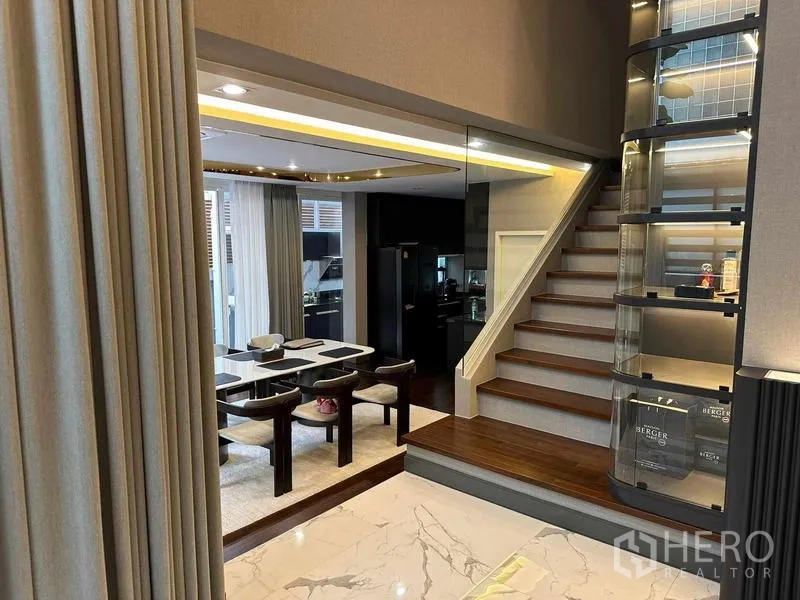 Detached House for sale in Suan Luang, Bangkok - Open-plan view from living to dining area with staircase and lit display shelves.