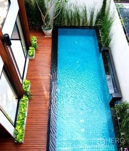 Detached House for rent in Khlong Toei, Bangkok - Aerial view of a narrow lap pool with wooden deck, planters and white privacy walls.