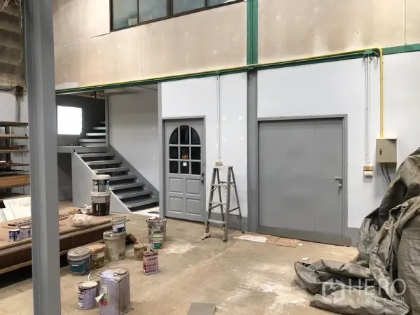 货栈 出租在Khlong Sam Wa, Bangkok - 仓库一层区域，通往夹层的楼梯、灰色门与设备区。