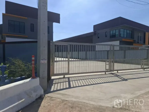 工厂 出租在Mueang Samut Sakhon, Samut Sakhon - 安全大门入口与大型混凝土场地，左右为现代厂房。