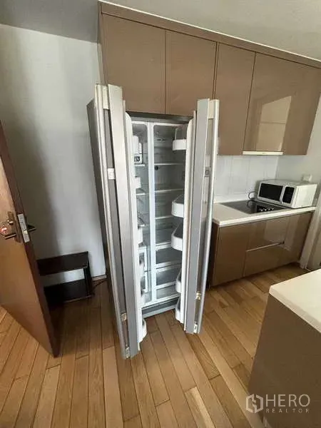 公寓 出租在Khlong Toei, Bangkok - 现代厨房，双门冰箱开启，配内置柜体。