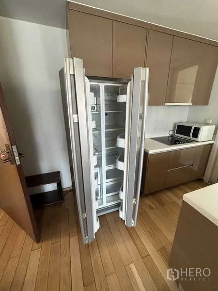 公寓 出租在Khlong Toei, Bangkok - 现代厨房，双门冰箱开启，配内置柜体。