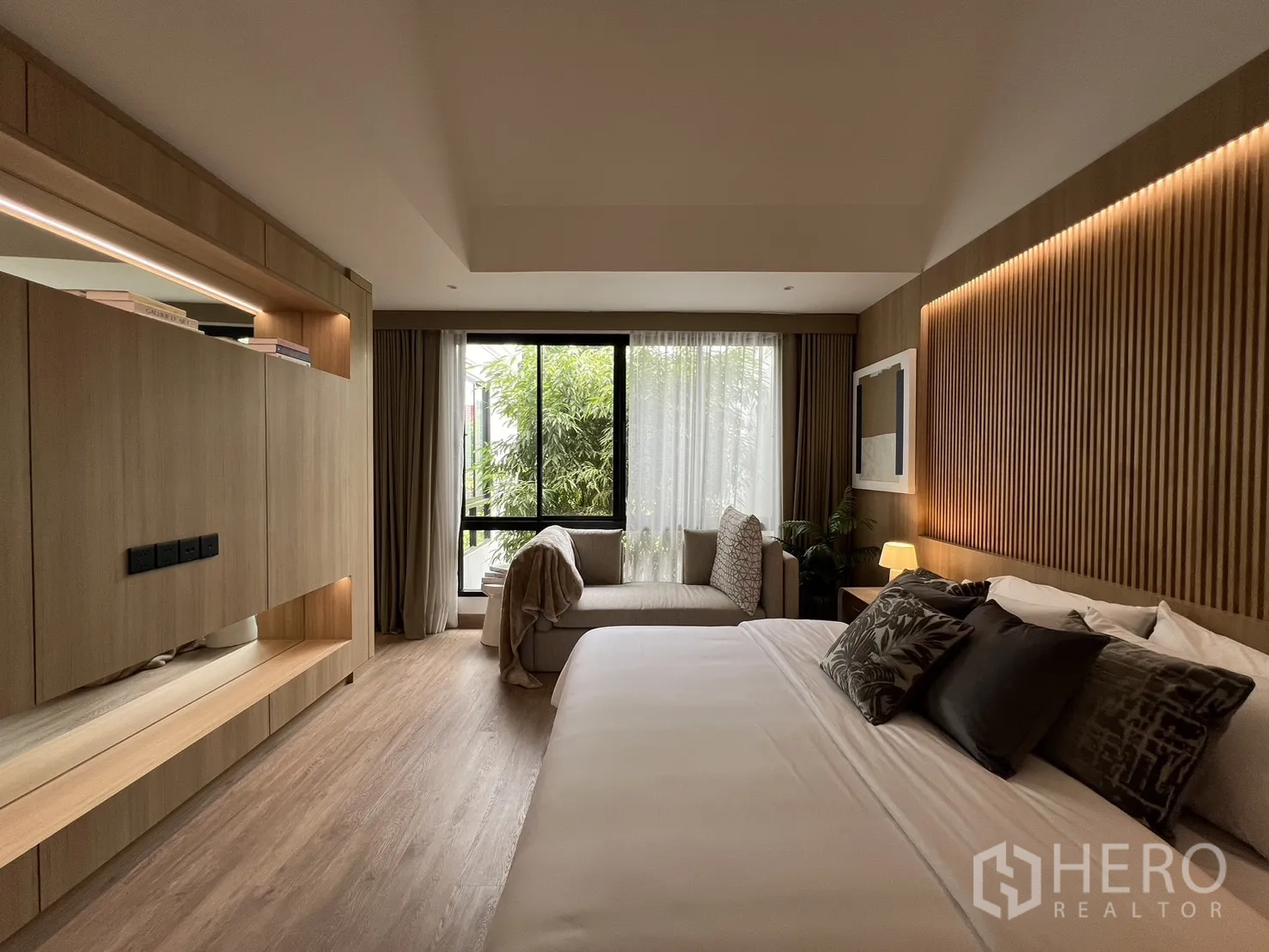 Townhouse for sale in Watthana, Bangkok - Primary bedroom close-up of bed, desk niche and wardrobes.