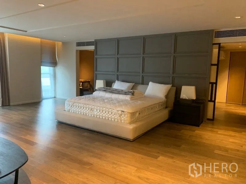 คอนโด ให้เช่าในWatthana, Bangkok - ห้องนอนใหญ่กว้าง ผนังหัวเตียงบานพาเนล พื้นไม้ และไฟสลัวนุ่มนวล