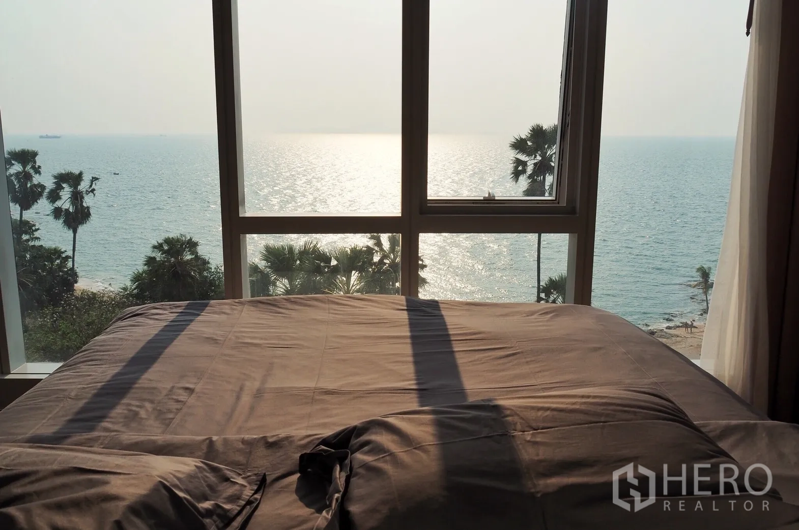 Condominium for rent in Bang Lamung, Chon Buri - Master bedroom with full-height window showcasing an uninterrupted sea view over the Gulf of Thailand.