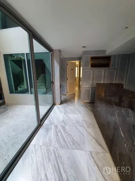 Office Space for rent in Khlong Toei, Bangkok - Hallway with sliding glass doors to an internal courtyard and a marble feature wall.