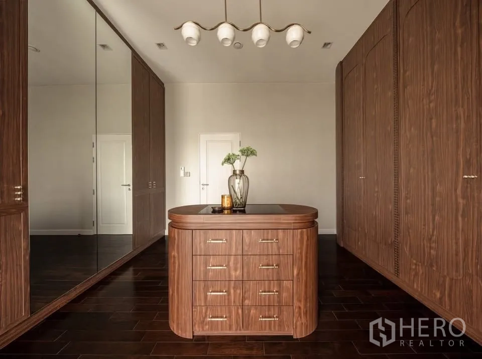Detached House for rent or sale in Lat Krabang, Bangkok - Spacious walk-in closet with wood wardrobes, mirrored doors, and a center island dresser.