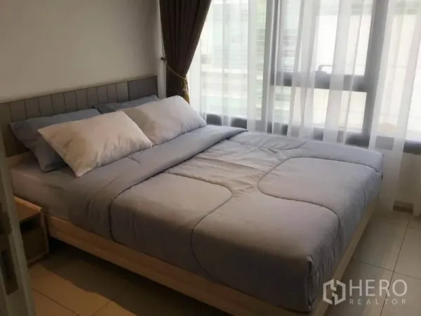 คอนโด ให้เช่าในWatthana, Bangkok - ห้องนอนมีหน้าต่างบานใหญ่ ผ้าม่านโปร่ง แสงธรรมชาติ และชุดเครื่องนอนสีเทา