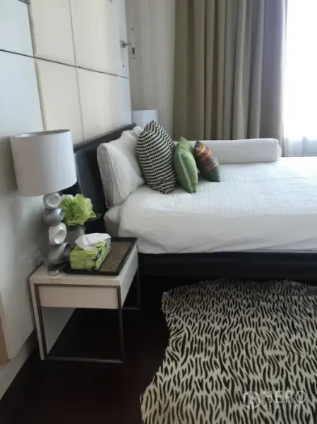 公寓 出租或出售在Ratchathewi, Bangkok - 卧室侧景，大床配彩色抱枕、斑马纹地毯和落地窗帘。