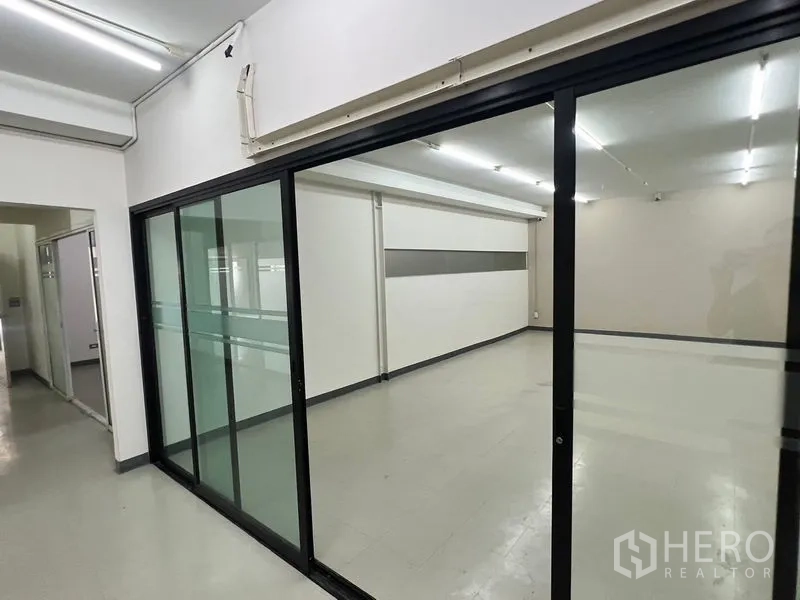 Warehouse for rent in Suan Luang, Bangkok - Open office room behind large glass partitions with ceiling lighting.