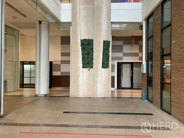 零售空间 出租在Khlong Toei, Bangkok - 现代商业中庭，挑高空间，玻璃店面、砖墙与瓷砖地面，设有垂直绿植墙