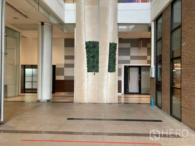 พื้นที่ขายปลีก ให้เช่าในKhlong Toei, Bangkok - โถงอาคารเชิงพาณิชย์สมัยใหม่ เพดานสูง หน้ากระจก ผนังอิฐ พื้นกระเบื้อง และสวนแนวตั้ง