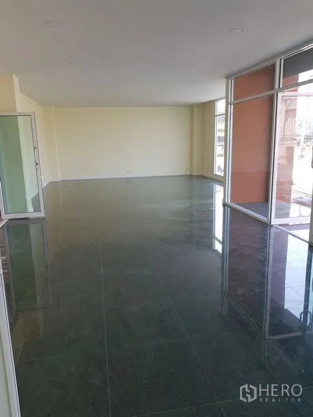 Factory for rent or sale in Mueang Samut Prakan, Samut Prakan - Open-plan showroom or office with glass walls and polished dark tiles.