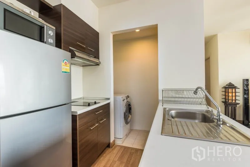 คอนโด ให้เช่าในBang Na, Bangkok - ครัวกะทัดรัดพร้อมตู้เย็นสแตนเลส เตาไฟฟ้า อ่างล้างจาน และมุมซักผ้าพร้อมเครื่องซักผ้า