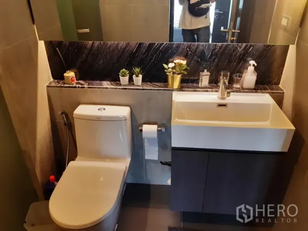 คอนโด ให้เช่าในKhlong Toei, Bangkok - ห้องน้ำสมัยใหม่พร้อมอ่างล้างหน้าแบบแขวน กระจกบานใหญ่ โถสุขภัณฑ์ และชั้นหินอ่อนตกแต่งต้นไม้กระถาง