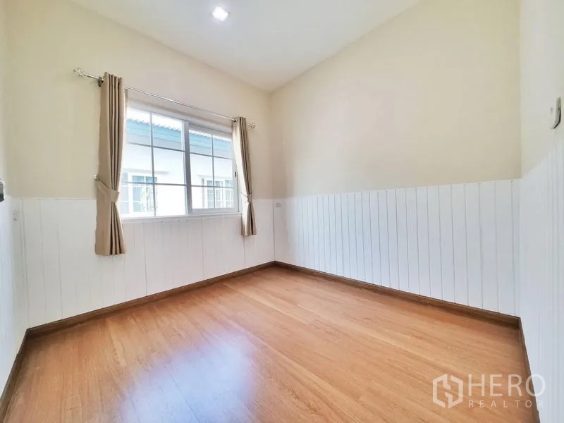 联排别墅 出租或出售在Phra Pradaeng, Samut Prakan - 采光充足的卧室，木地板、半墙护板和带窗帘的大窗。