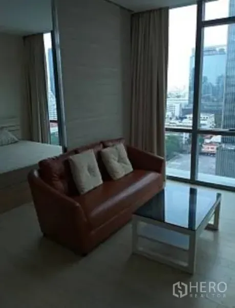 公寓 出租在Watthana, Bangkok - 客厅配皮沙发与玻璃茶几，落地窗俯瞰城市天际线。