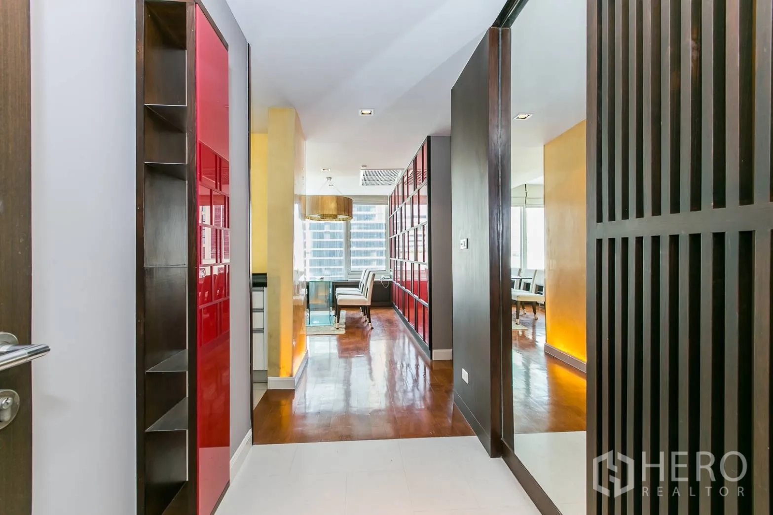 คอนโด ให้เช่าหรือขายในKhlong Toei, Bangkok - โถงทางเข้ามีชั้นสีแดง กระจกเงา และพื้นไม้ นำสู่พื้นที่นั่งเล่น