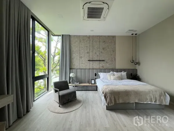 Detached House for rent in Saphan Sung, Bangkok - Corner bedroom with floor-to-ceiling windows, designer headboard and neutral decor.