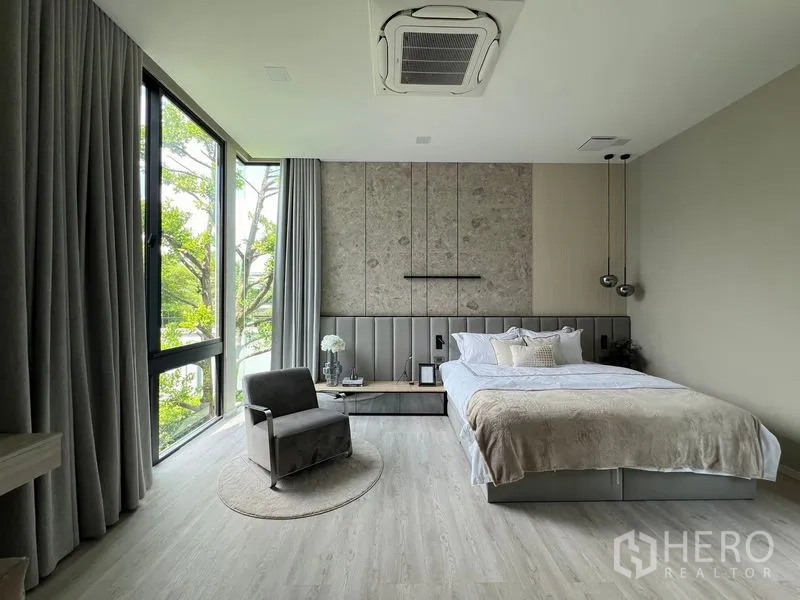 Detached House for rent in Saphan Sung, Bangkok - Corner bedroom with floor-to-ceiling windows, designer headboard and neutral decor.