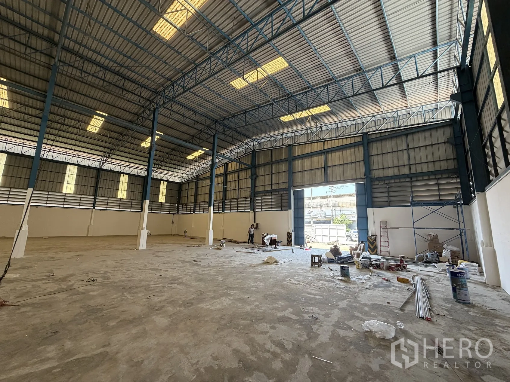 Factory for rent in Bang Sao Thong, Samut Prakan - Warehouse loading area showing wide shutter door, concrete floor and equipment during fit-out.