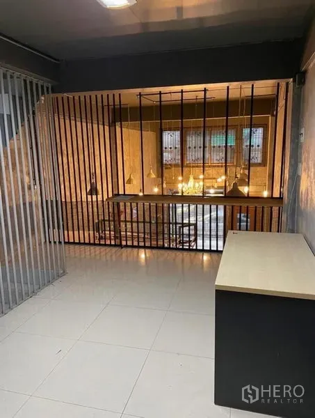 Shophouse for rent in Chatuchak, Bangkok - Mezzanine workspace with vertical metal slats overlooking the double-height area.