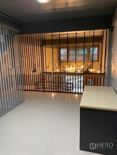 Shophouse for rent in Chatuchak, Bangkok - Mezzanine workspace with vertical metal slats overlooking the double-height area.
