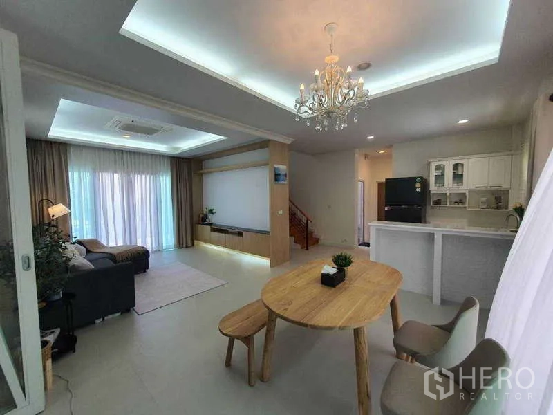 Detached House for rent in Saphan Sung, Bangkok - Dining area next to kitchen peninsula with chandelier and staircase in view.