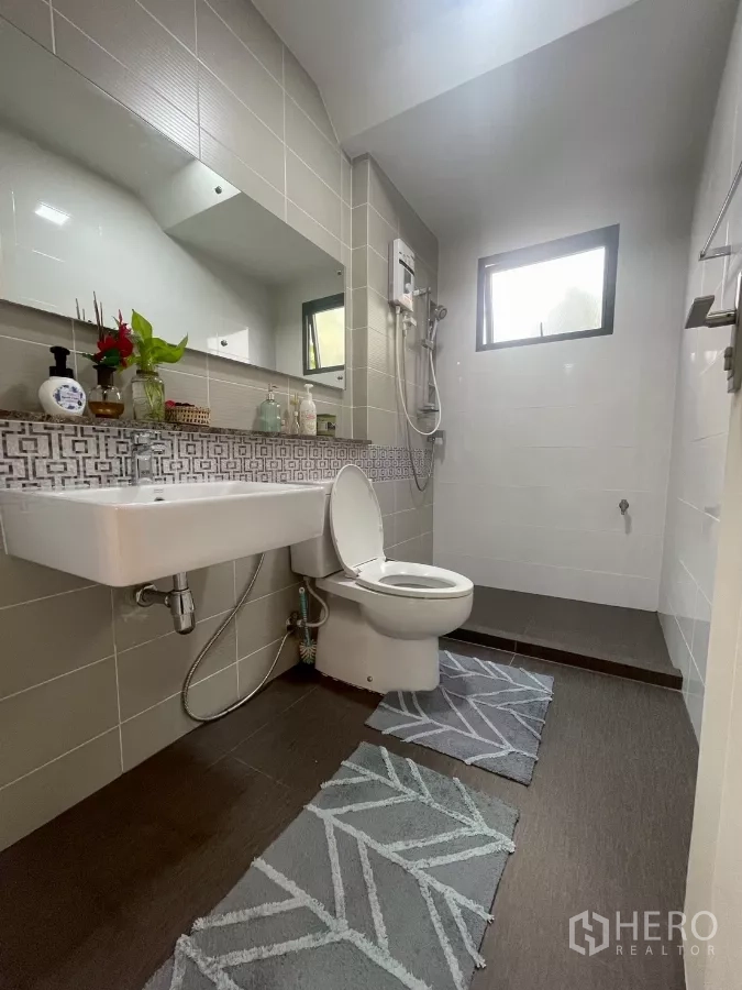 Detached House for sale in Bang Phli, Samut Prakan - Second bathroom with shower heater, wide mirror and patterned accent tiles.
