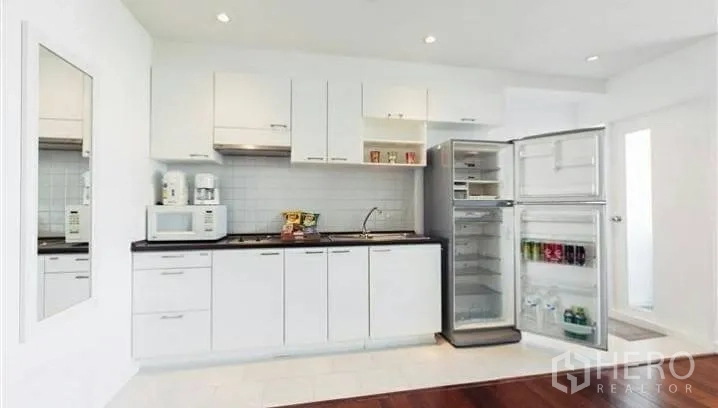 公寓 出租或出售在Watthana, Bangkok - 简洁白色厨房，带橱柜、灶台、水槽与敞开式冰箱。