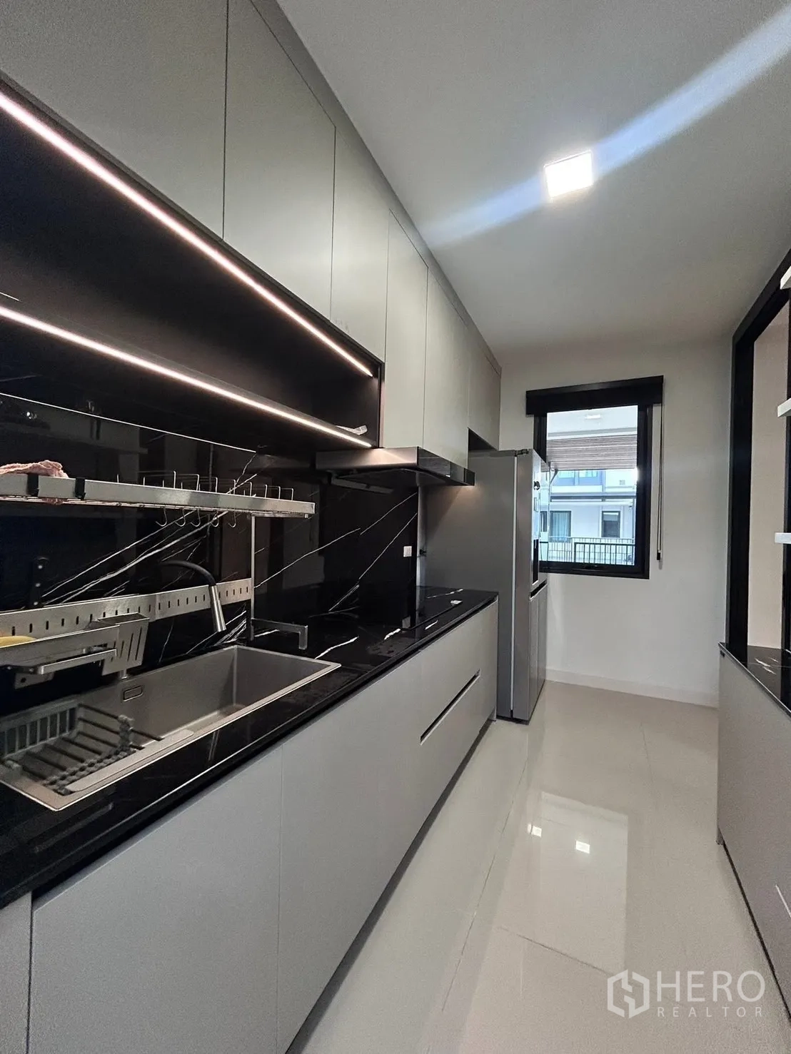 Semi-detached House for rent in Bang Phli, Samut Prakan - Sleek galley kitchen with black stone countertops, sink, cooktop, and LED lighting.