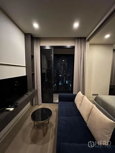 Condominium for rent in Watthana, Bangkok - Built-in work nook with desk, chair, and brass sconce beside the bed.
