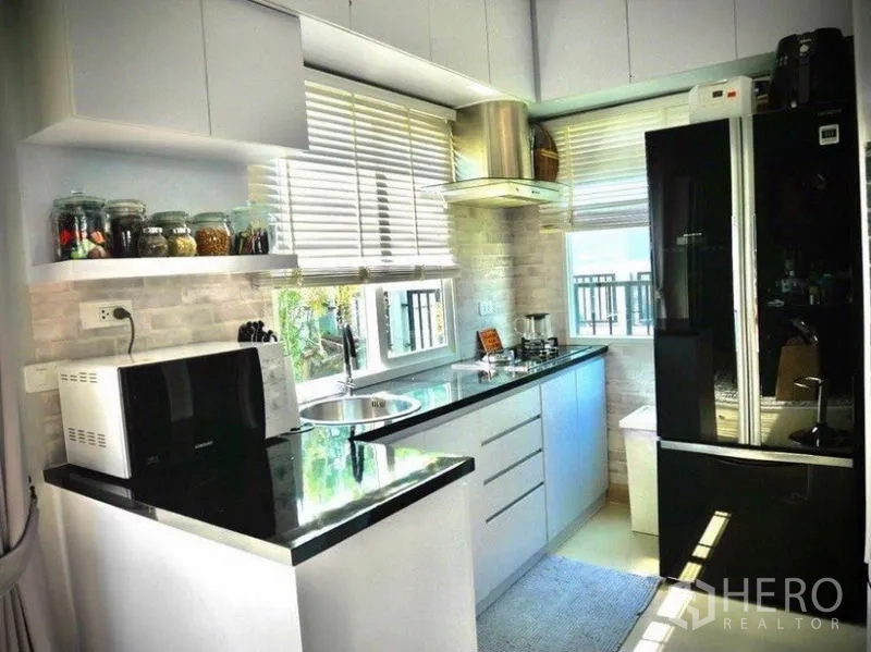 Detached House for rent or sale in Bang Phli, Samut Prakan - L-shaped kitchen with white cabinetry, black countertops, windows and range hood