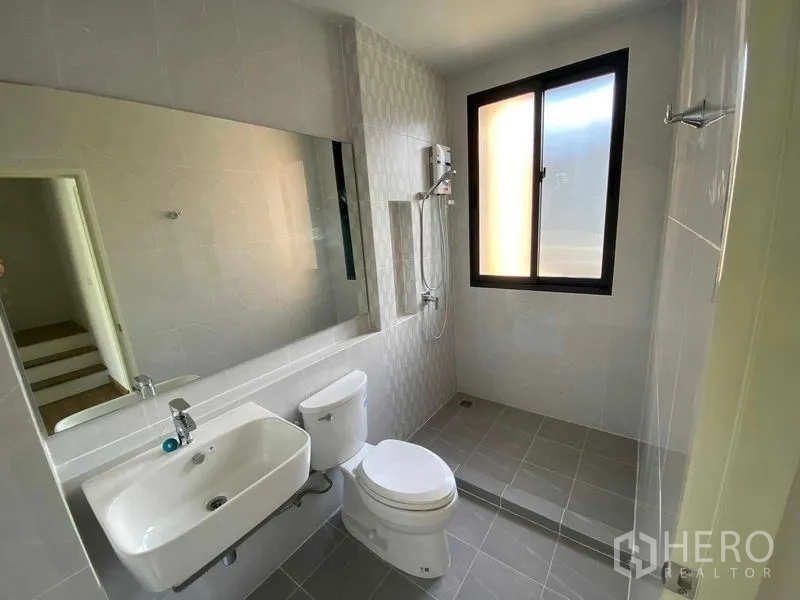 联排别墅 出租在Prawet, Bangkok - 明亮卫浴，超大镜面、马桶、台盆与步入式淋浴区。