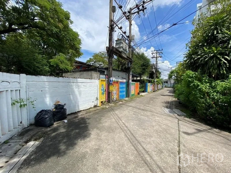 Detached House for rent in Watthana, Bangkok - Quiet alley entrance with painted boundary wall and overhead cables.