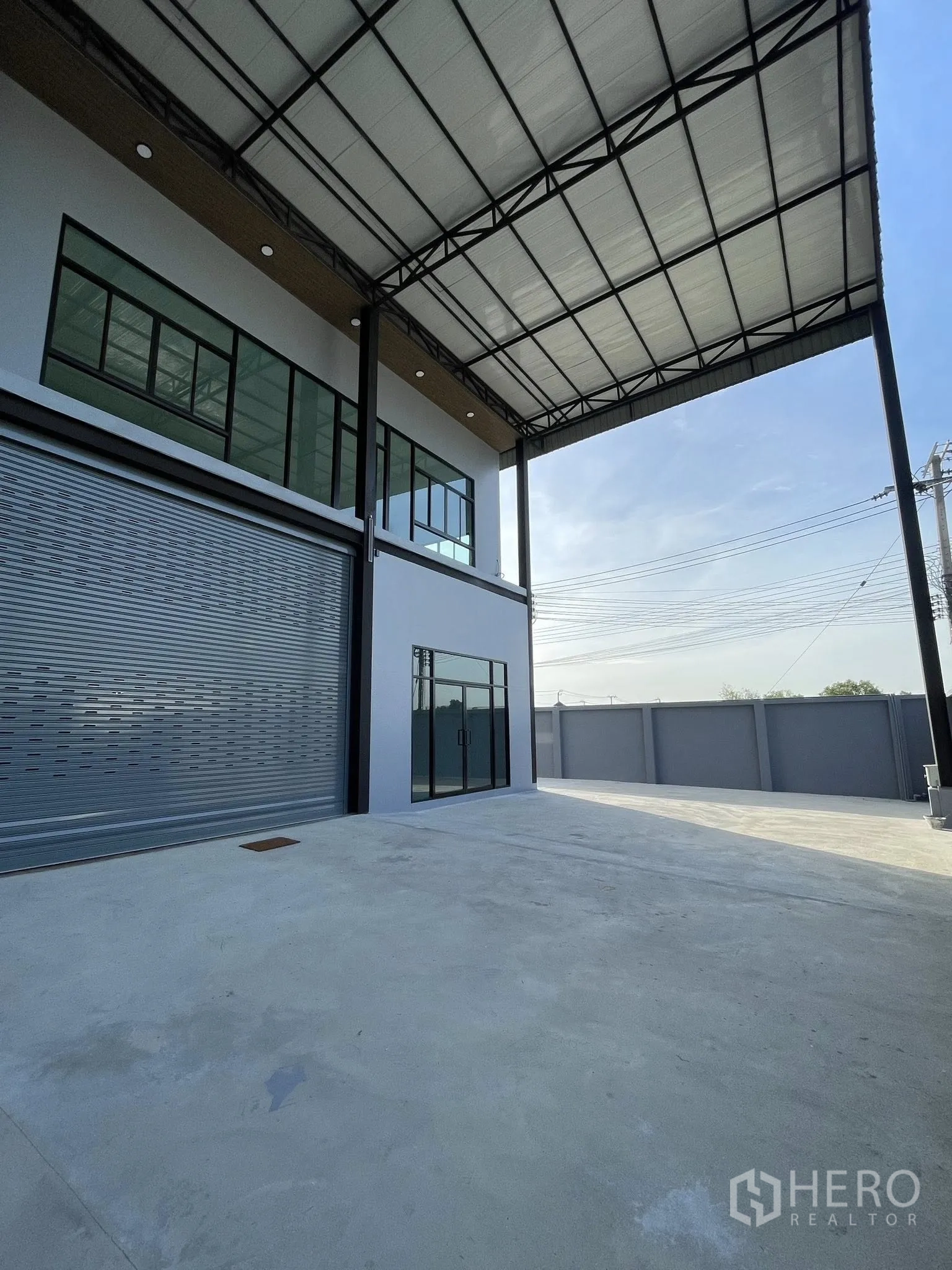 Warehouse for rent in Phra Samut Chedi, Samut Prakan - Front loading bay with wide roller shutter door under a deep canopy.