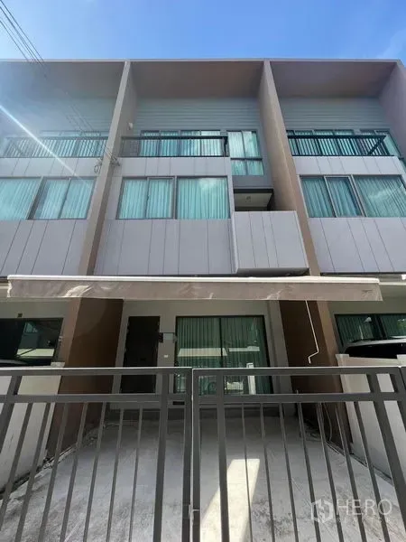 Townhouse for rent in Saphan Sung, Bangkok - Three-storey townhouse facade with balconies, large windows and a front gate.