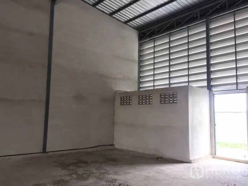Warehouse for rent in Sai Noi, Nonthaburi - Interior corner with built-in utility block and side exit door beneath louvered windows.