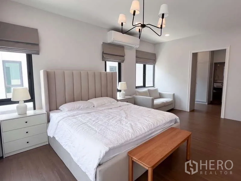 Detached House for rent or sale in Bang Phli, Samut Prakan - Spacious master bedroom with tall upholstered headboard, sofa corner and ensuite access.
