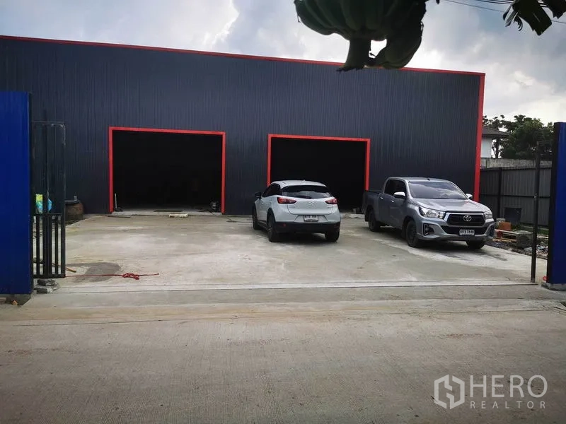 Warehouse for rent - Modern black metal warehouse facade with three wide loading bays and paved parking.